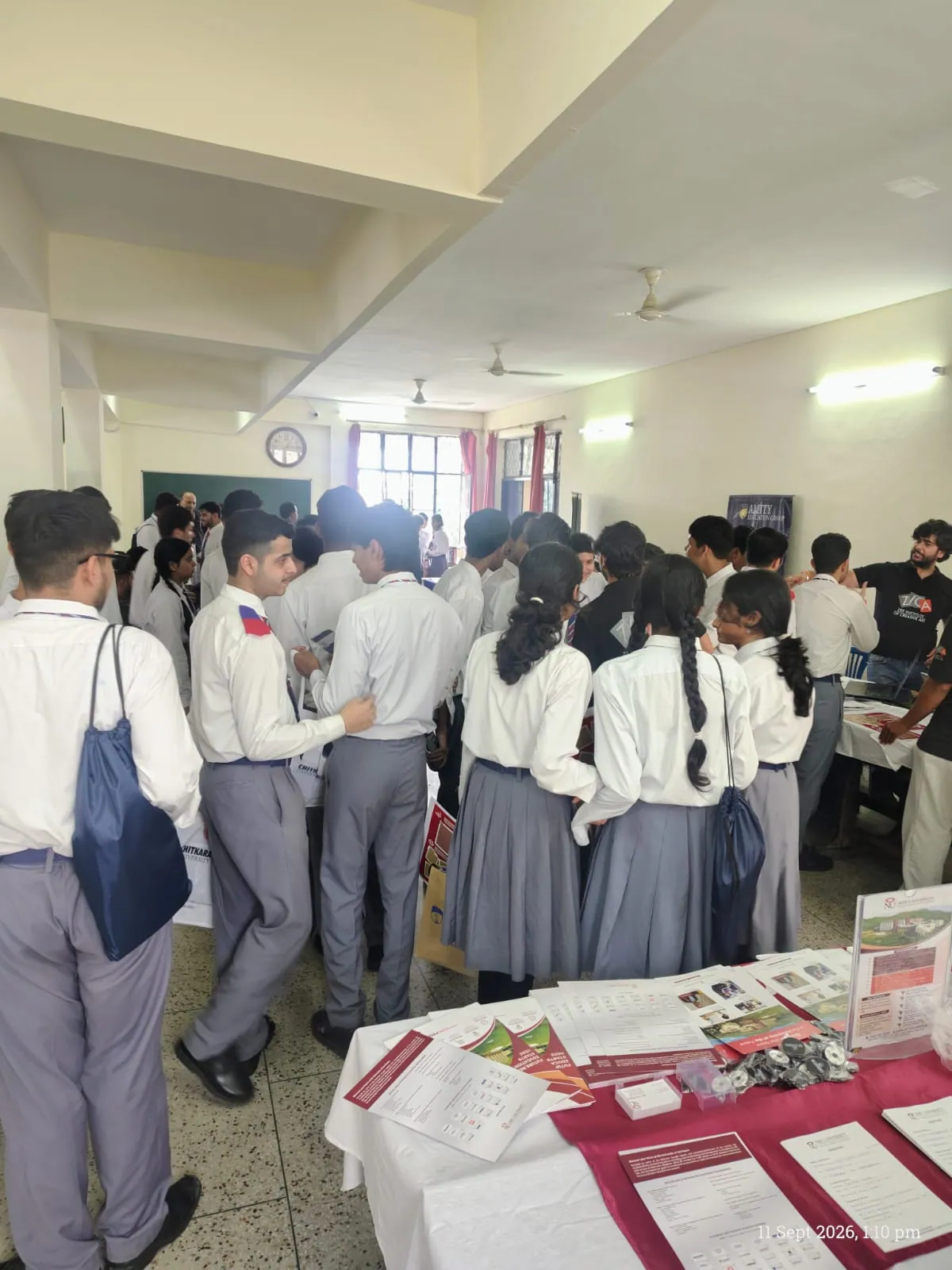 Students exploring multiple university booths and flyers at school career fair